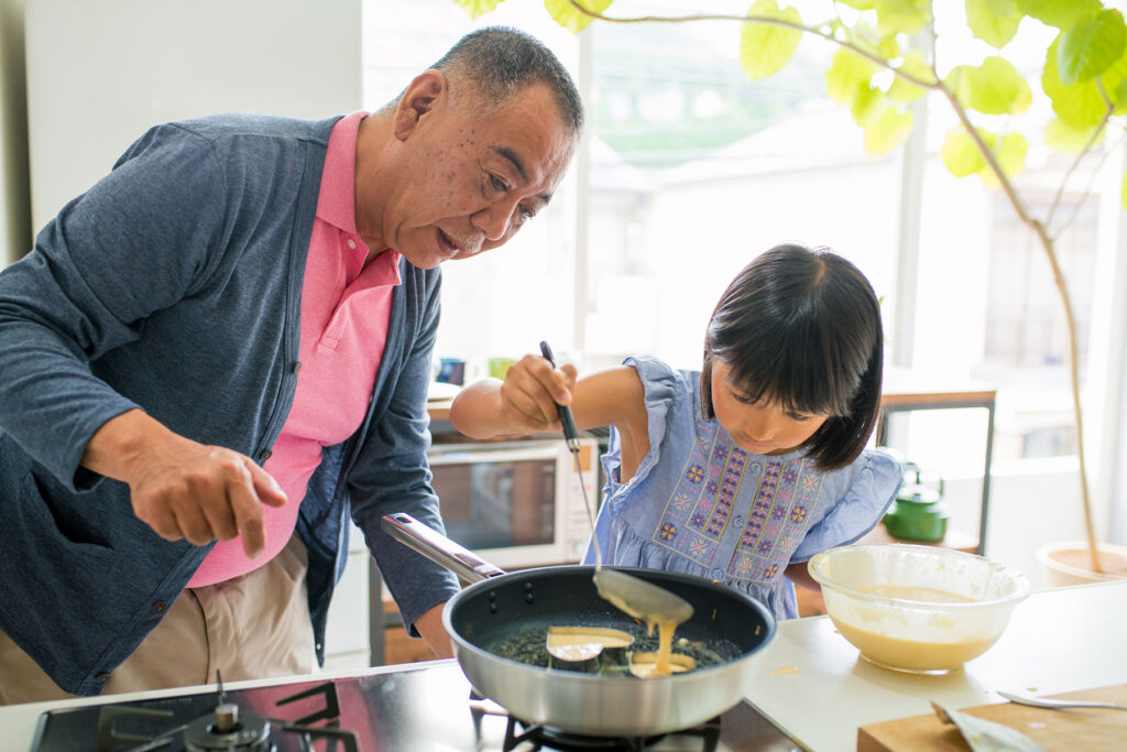 Senior asian grandfather cooking with granddaughter