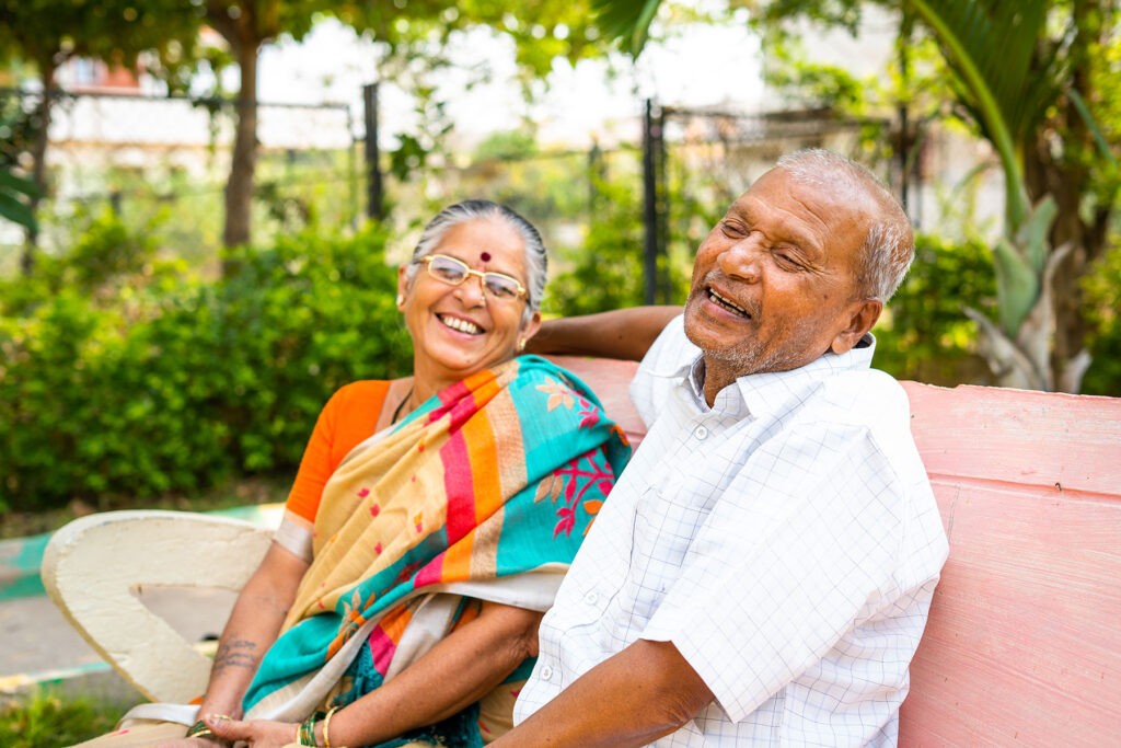 senior Indian couple laughing on park bench