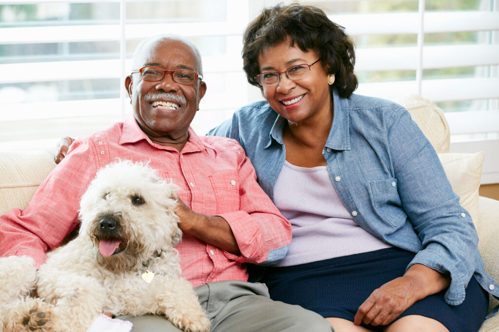 Senior African American couple sitting on couch with dog
