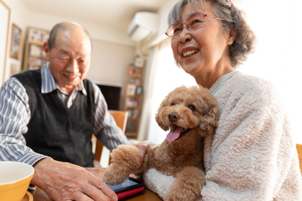 Senior Asian couple holding dog and smiling