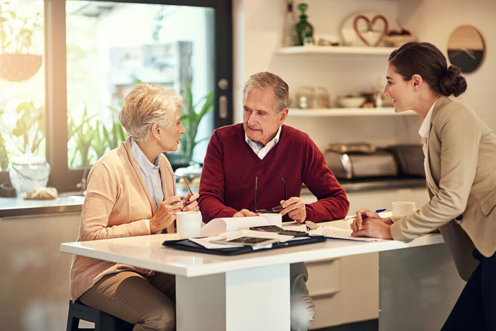 senior couple discussing reverse mortgage details with woman