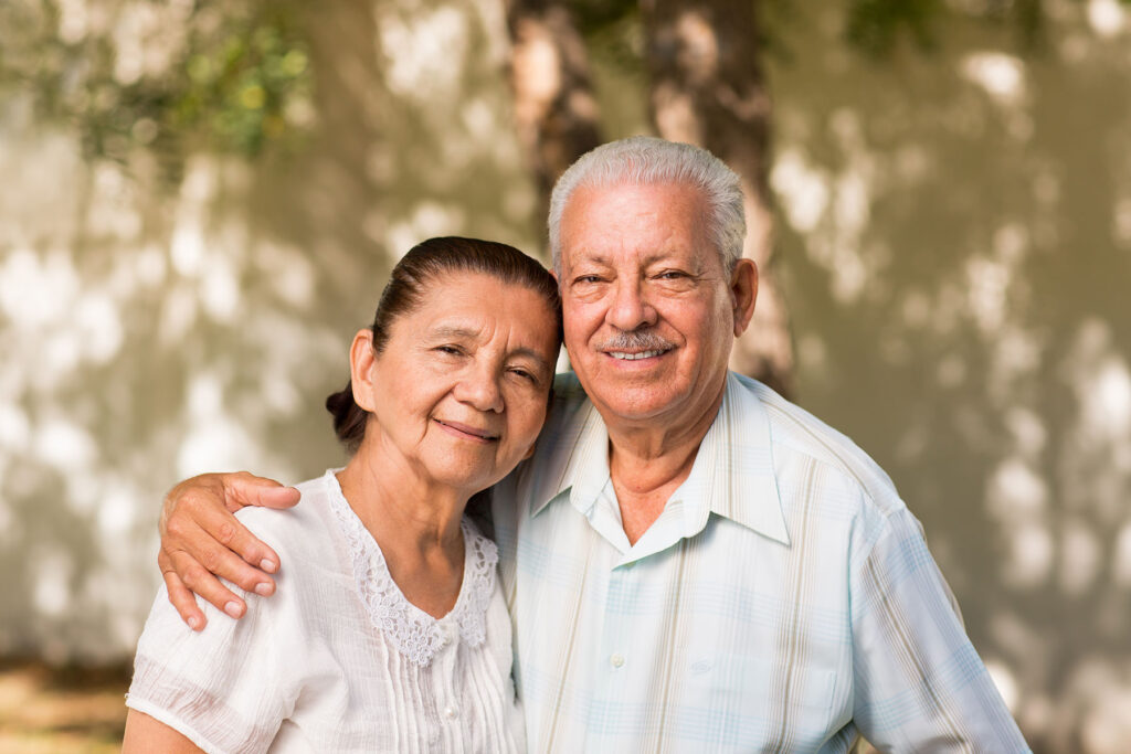Senior Hispanic couple with arms around each other smiling