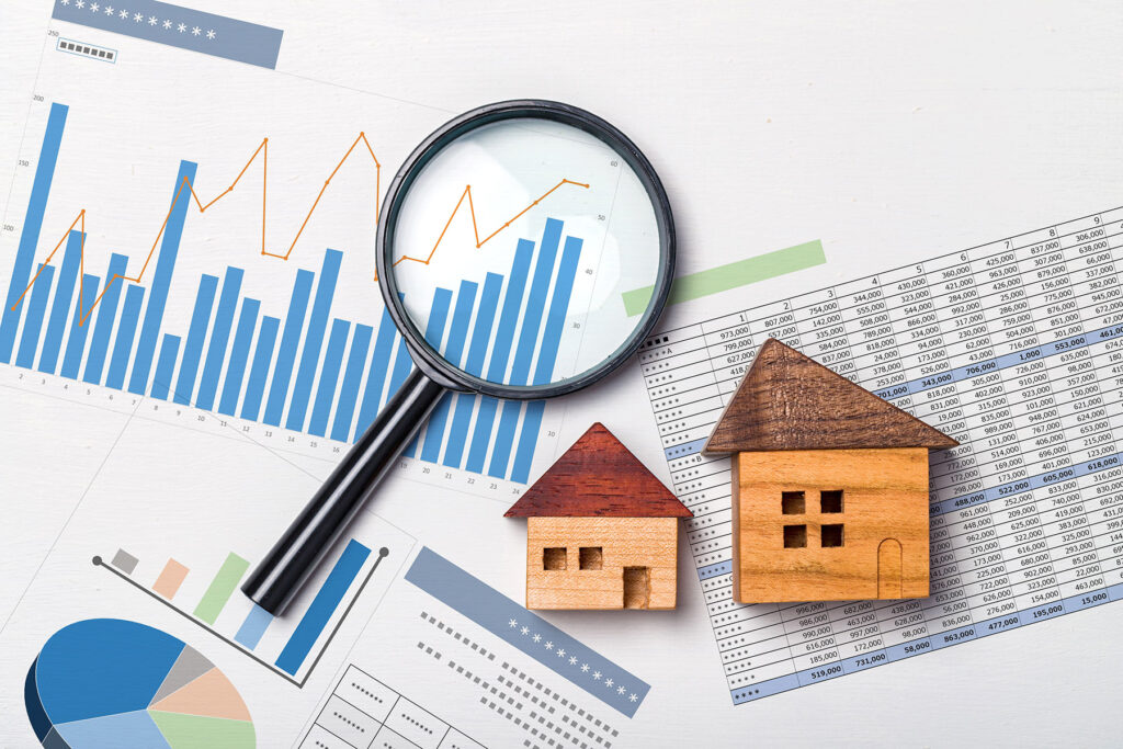 toy house on charts with magnifying glass